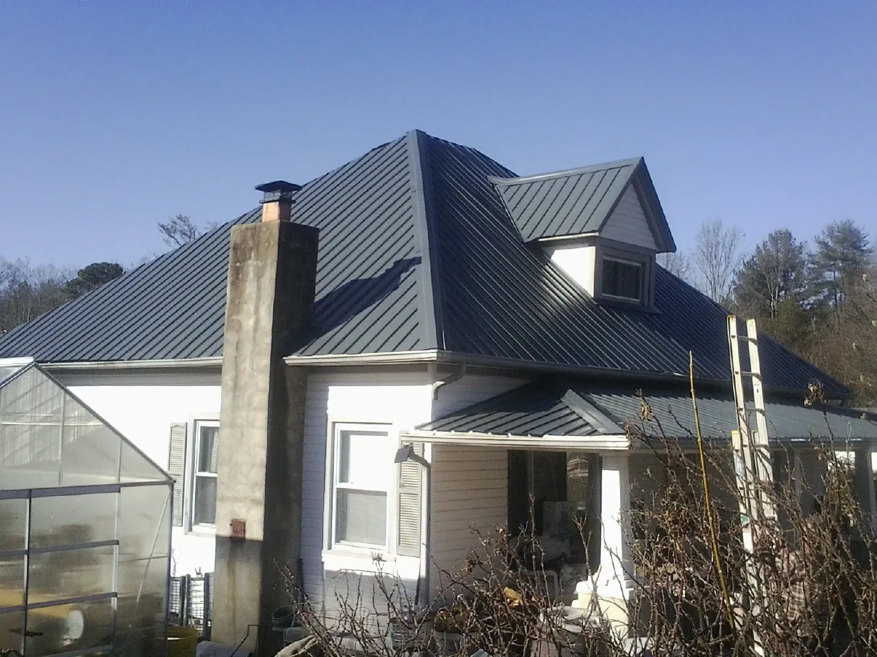 Dark blue standing seam metal roof on a white farmhouse with dormer — Slate & Tile Roof Repair by Roofing Brothers in Melfa