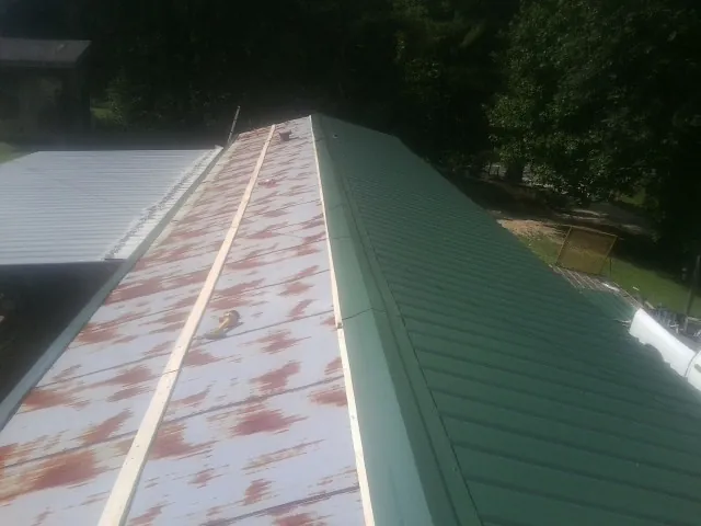 Old rusted panels beside newly installed green metal roofing — Wind Damage Roof Repair by Roofing Brothers in Melfa