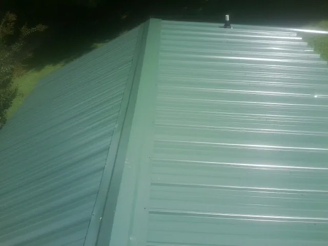 New green metal panels meeting at the ridge of a roof — Flat Roof Repair work by our crew in Melfa
