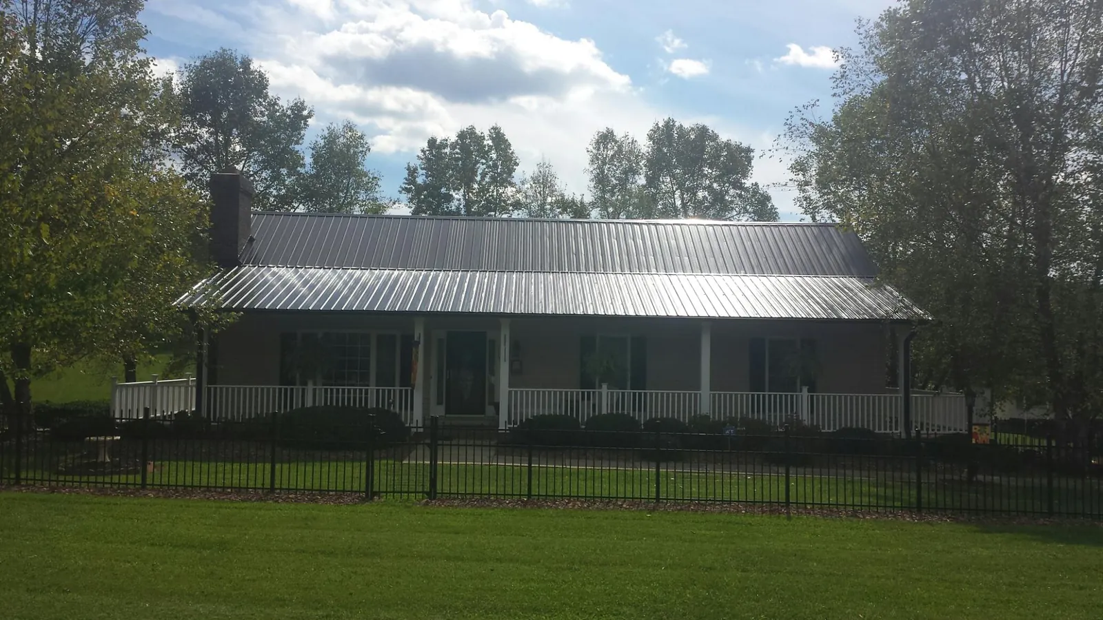 Gray metal roof on a brick ranch with a full width front porch — Gutter Guard Installation work by our crew in Melfa