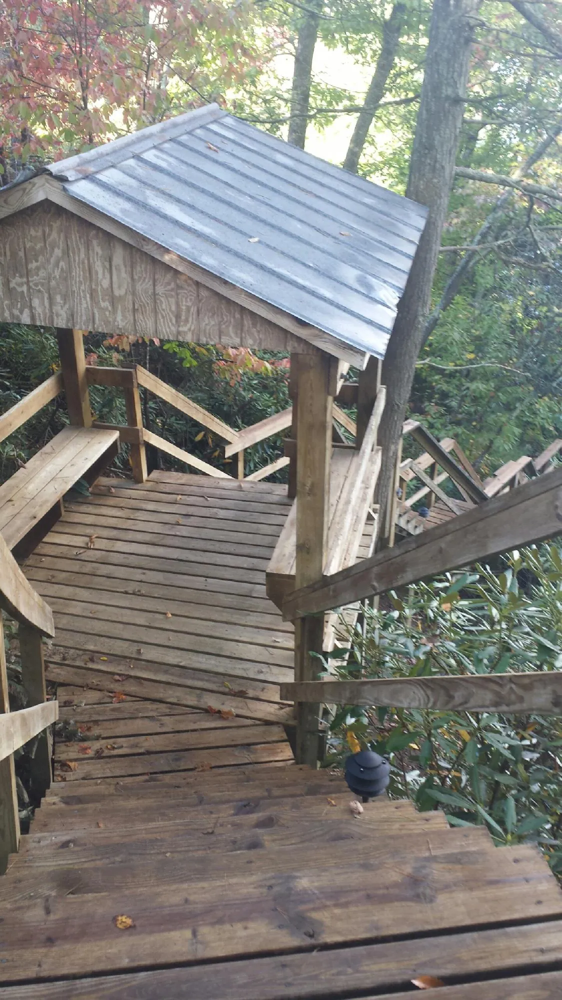 Metal roofed shelter over wooden steps on a wooded walkway — Skylight Repair & Installation work by our crew in Melfa